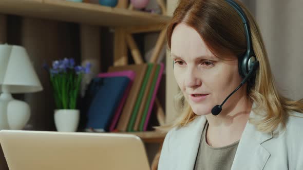 The Woman Communicates with Customers From Home Speaks in the Headset alt