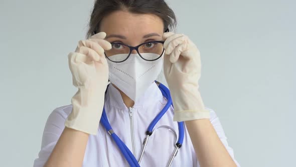 Female Doctor is Putting Off Protective Blue Gloves Isolated on White Background After Some Medical alt
