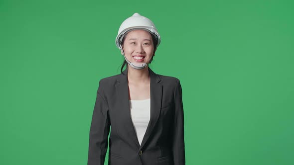 Smiling Asian Female Engineer Looking Around While Walking In The Green Screen Studio alt