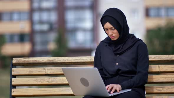 Focused Freelancer Modern Muslim Woman Working Use Laptop Outdoor Sitting on Bench at City Building alt