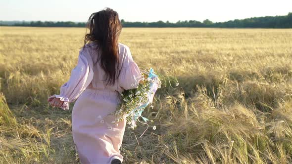 Back View of Girl in Wheat Field. Beautiful Woman in Dress with Ripe Wheat in Hands alt