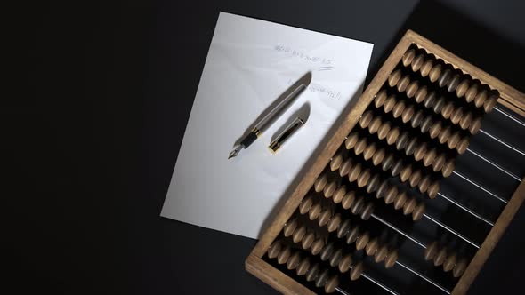 Vintage wooden abacus with fountain pen and paper with written calculations.