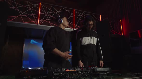 Contemporary Trendy Multiracial Djs Talking During Live Performance at Stage in Nightclub alt