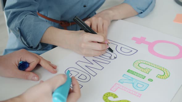 Closeup of Female Hands Drawing Colorful Girl Power Banners Fighting for Gender Equality alt