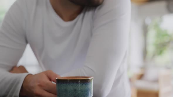 Man sitting with coffee and looking away at dining table in a comfortable home 4k alt