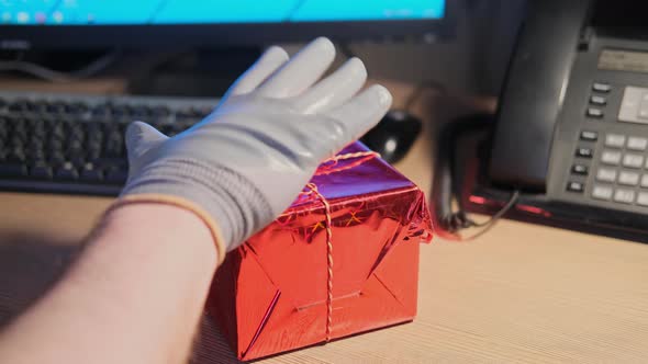A man in gloves steals a gift from an office desk on Christmas and New Year