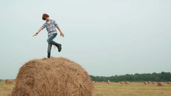Stylish Teenage Boy Posing on Haystack in Field