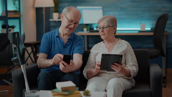 Modern Couple Using Smartphone and Digital Tablet at Home alt