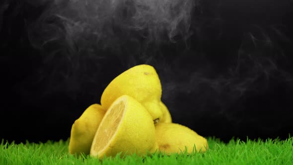 Smoke falling over a rotating pile of lemons placed on nicely trimmed grass alt