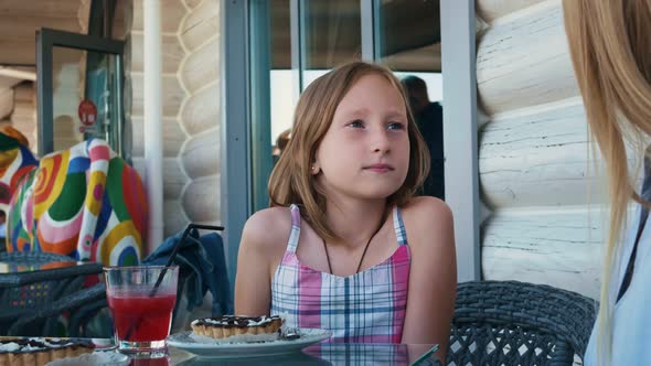 A Lovely Girl and a Young Woman are Sitting on a Summer Veranda alt