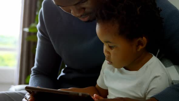 Close-up of young black father and son using digital tablet in a comfortable home 4k alt