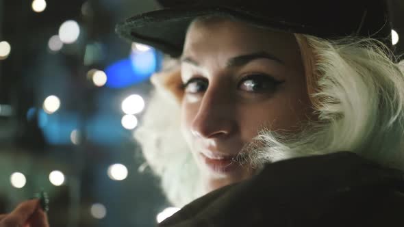 Cinematic Portrait of Young Funky Woman Outdoor in Wintertime at Night Having Fun Looking at Camera alt