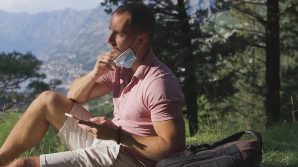 Man Taking Off Medical Face Mask and Breathing Air in Mountains Outdoors alt