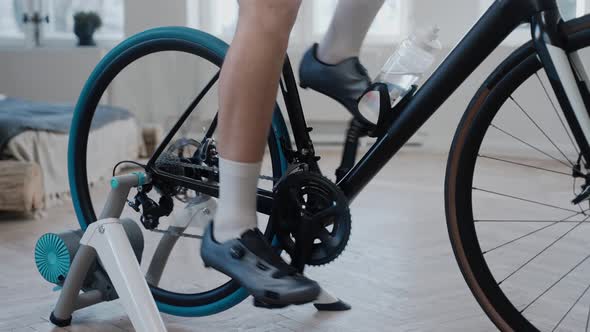 Close Shot of a Cyclist's Legs Training on an Exercise Bike at Home