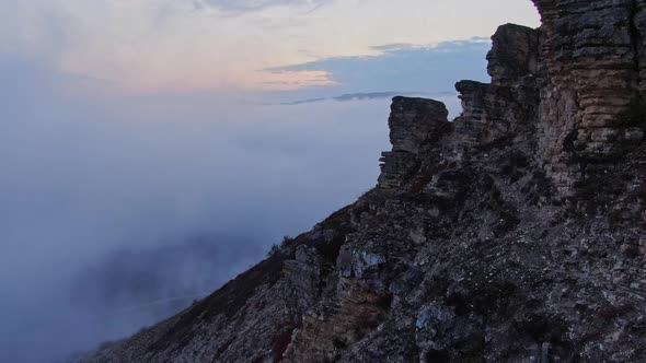 Flying Along the Cliff with Traces of Weathered Rock Against the Background of a Mountain Range