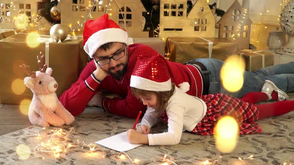 Family Father and Girl Write Letter to Santa Claus on Background of Christmas Tree alt