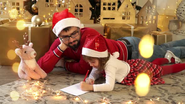 Family Father and Girl Write Letter to Santa Claus on Background of Christmas Tree