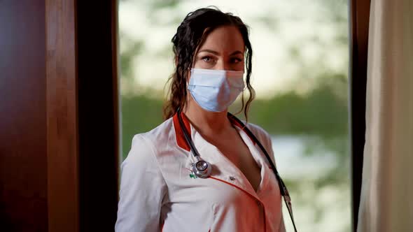 Dolly in View of Young Female Doctor or Nurse Wearing Surgical Face Mask and White Gown and Looking alt