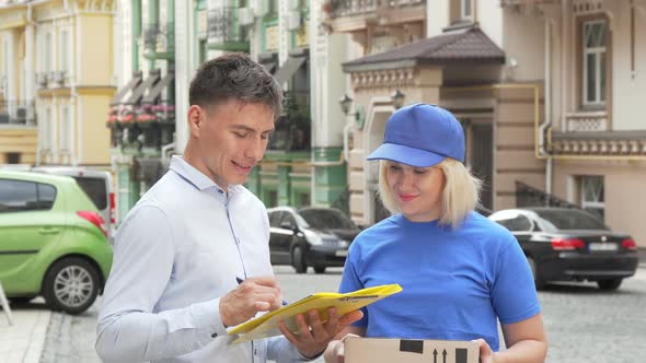 Female Courier Delivering a Package To Young Man on City Street