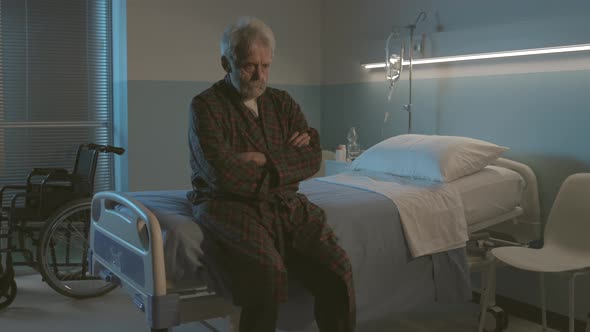 Sleepless senior man sitting on a hospital bed