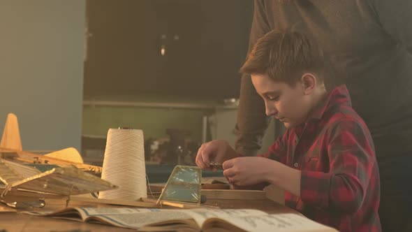 A Boy Constructs an Airplane Under the Guidance of a Teacher alt