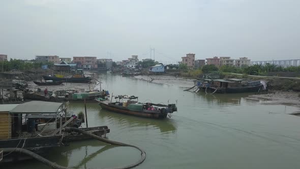 Aerial shot of a maintenance boat approaching a berth on a polluted river in Asia alt
