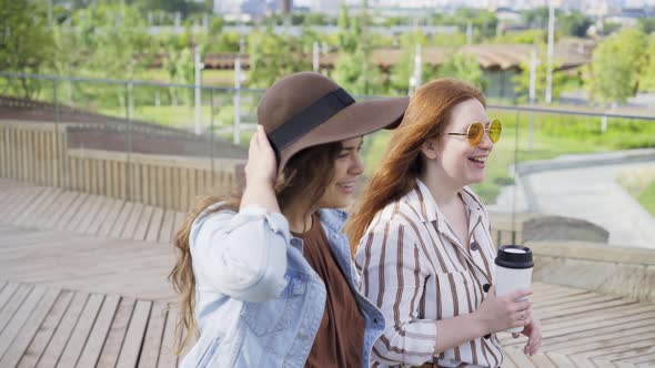 Stylish Women with Coffee Walk Along Contemporary City Park