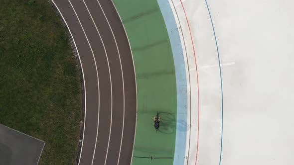 Drone Top View of Female Cyclist on Road Bike Training at Velodrome Slowly Preparing for Race alt