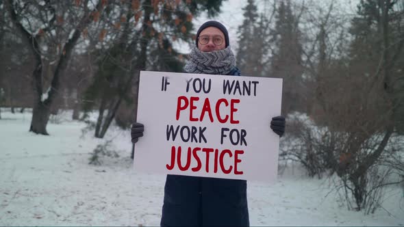 Man Showing Off a Banner Which Says If You Want Peace Work For Justice. Protest alt