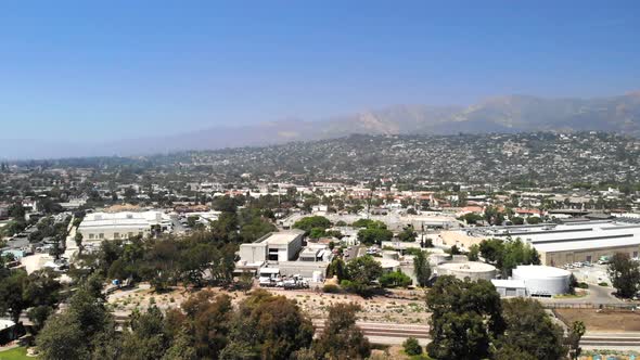 Aerial shot flying over the city buildings and luxury homes with mountains in the distance in downto alt