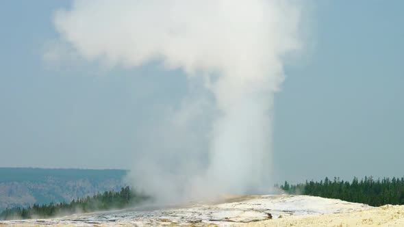 Old Faithful Geyser in Yellowstone National Park ejecting hot steam water alt