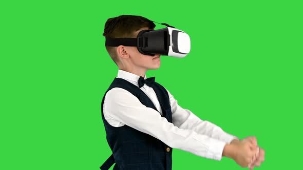 Excited Boy in Formal Wear Playing the Sword Game in Virtual Reality Goggles on a Green Screen alt
