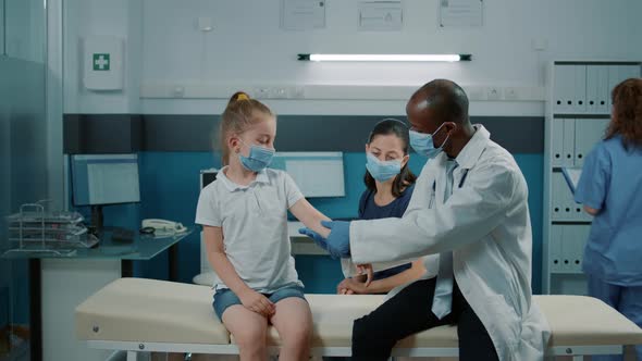 Physician Consulting Little Girl with Arm Injury at Exam Appointment alt