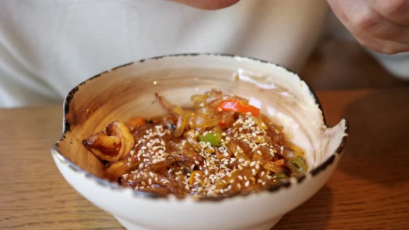 Unrecognizable Woman Eating Transparent Noodles with Seafood in a Cafe alt