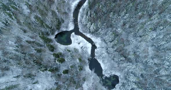 Aerial View of Spring Water Lake and River in Snowy Winter Forest alt