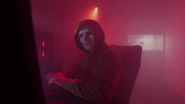 Anonymous Person in a White Mask Works on the Computer Inputs Code Types Very Fast on the Keyboard alt