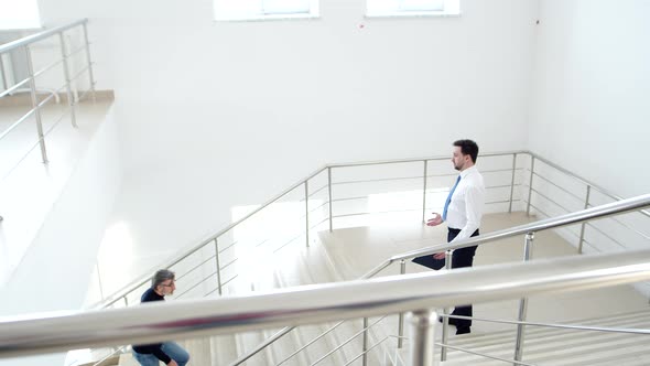 Manager Meets Client Coming Up Stairs and Shakes Hand Side View alt