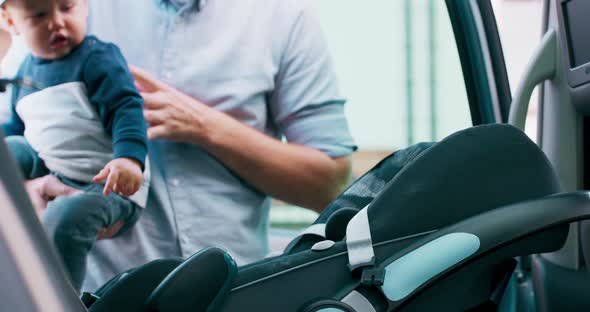 Camera Inside the Car Closeup Baby Car Seat Door Opens and Baby Boy Appears Carried By His Young alt