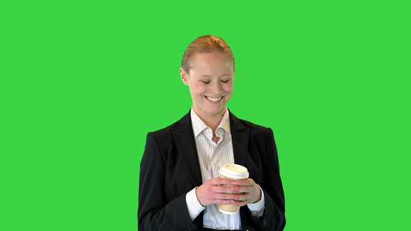 Beautiful Young Blond Business Woman Walking Holding a Cup of Coffee on a Green Screen Chroma Key alt