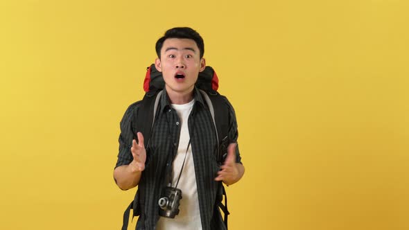 Young Asian tourist man with backpack feeling excited smiling and taking picture with camaera