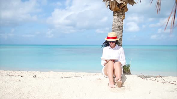 Young Woman Reading Book During Tropical White Beach alt
