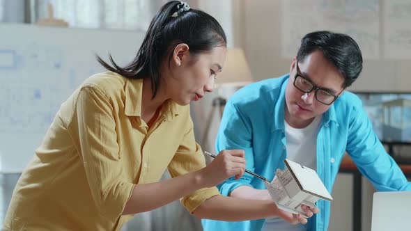 Asian Woman And Man Engineers Holding Paper Model Of House Discuss About Design At The Office alt