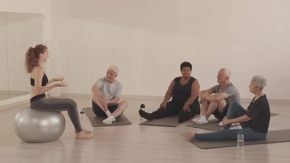 Group of Seniors on Mats Listening to Coach at Yoga Class alt