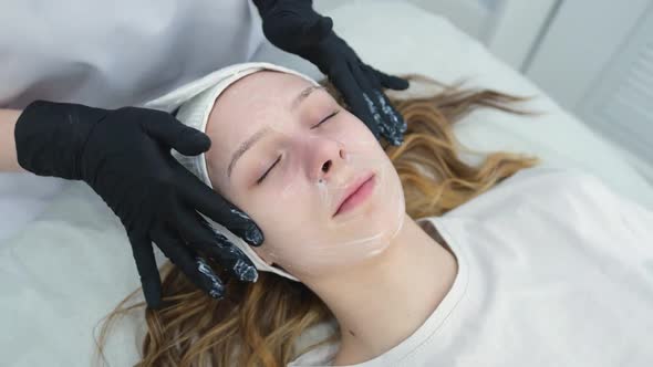 Cosmetologist Applies a Woman a Therapeutic Mask on Her Face alt