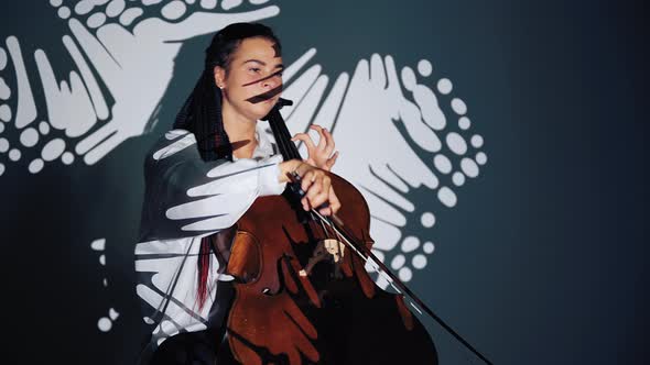 Woman in Spotlight in Studio Plays on Violoncello