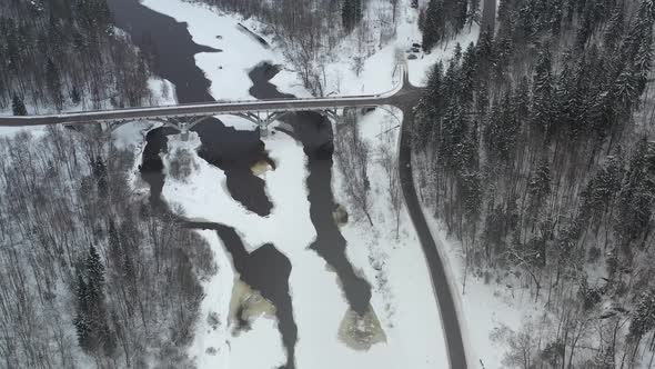 High Aerial View of a bridge over river Gauja in  Sigulda, Latvia in a snowstorm