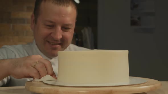 Man Pastry Chef Smiles and Aligns the Cake Mold