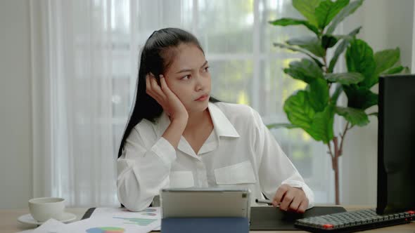 stay-at-home Asian businesswoman sits stressed and contemplating on a timely task at her desk