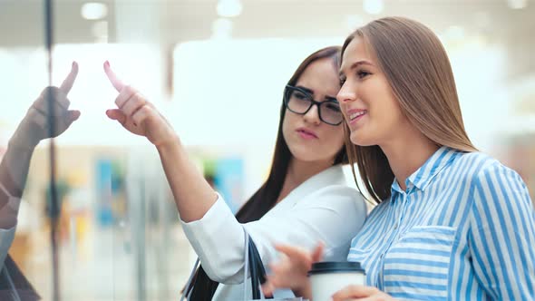 Two Beauty Young Woman Friends Discussing Something Behind the Storefront in a Shopping Mall alt