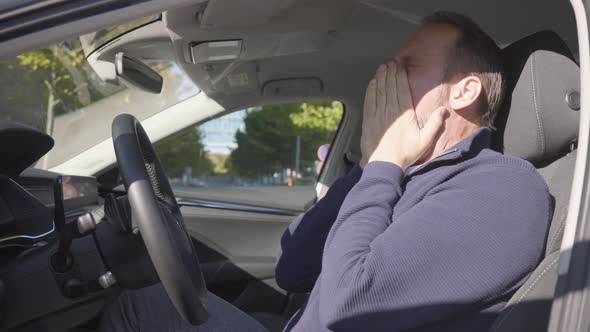 A Middleaged Handsome Caucasian Man is Tired and Yawns in a Car  Side Closeup